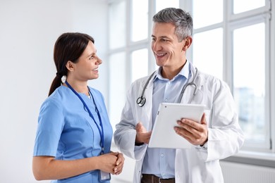 Smiling healthcare workers with tablet in hospital