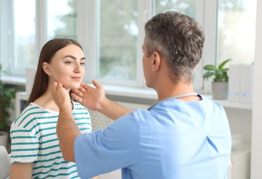 Doctor examining woman's throat in clinic during appointment