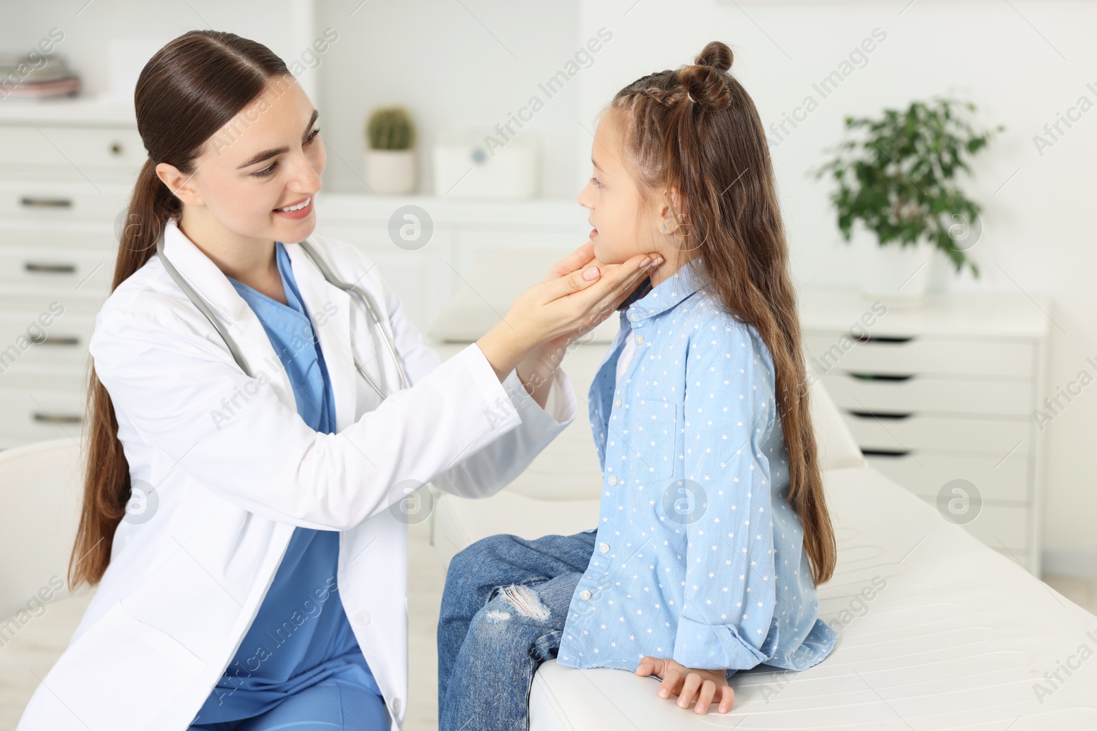 Photo of Doctor examining girl's throat in clinic during appointment