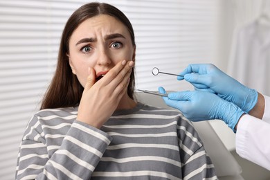 Dental phobia. Dentist working with scared woman in clinic, closeup