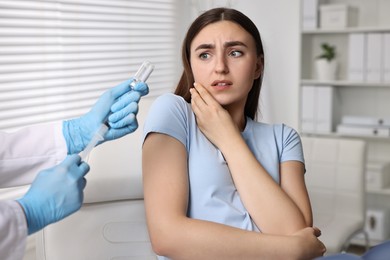 Dental phobia. Dentist with syringe and vial near scared woman in clinic, closeup