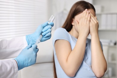 Dental phobia. Dentist with syringe and vial near scared woman in clinic, closeup