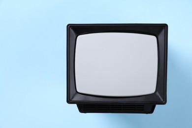 Photo of Retro tv set on light blue background, top view. Space for text