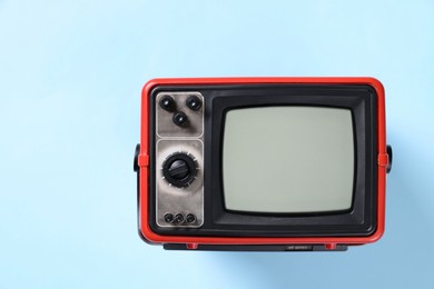 Photo of Retro tv set on light blue background, top view. Space for text