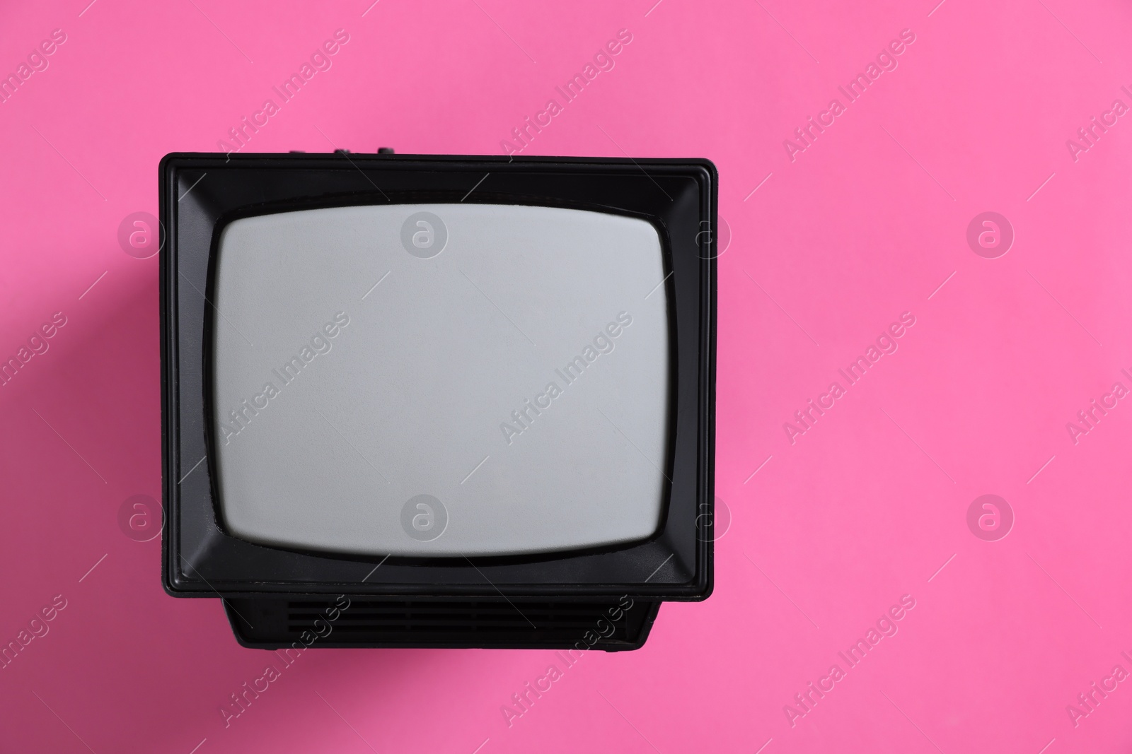 Photo of Retro tv set on pink background, top view. Space for text