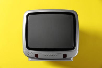 Photo of Retro tv set on yellow background, top view