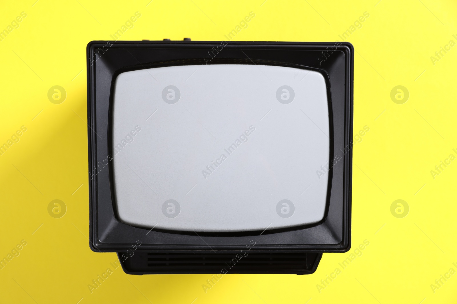 Photo of Retro tv set on yellow background, top view