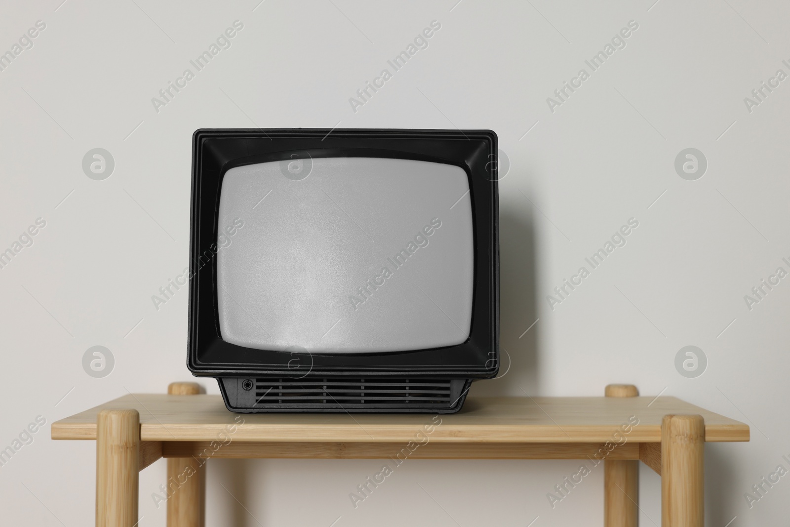 Photo of Retro tv set on wooden shelf against white wall