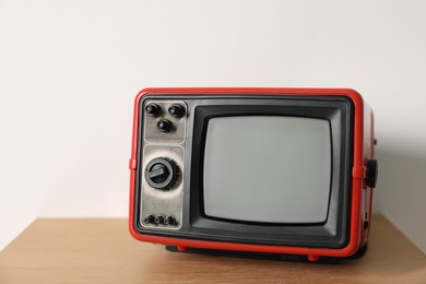 Photo of Retro tv set on nightstand against white wall. Space for text