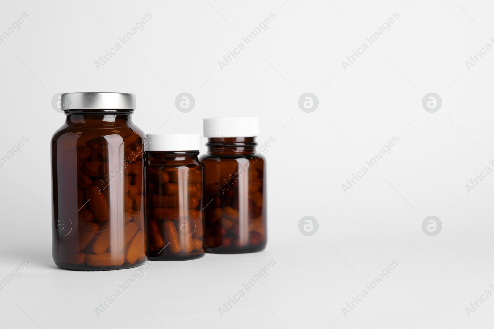 Photo of Medical bottles with pills on white background, space for text