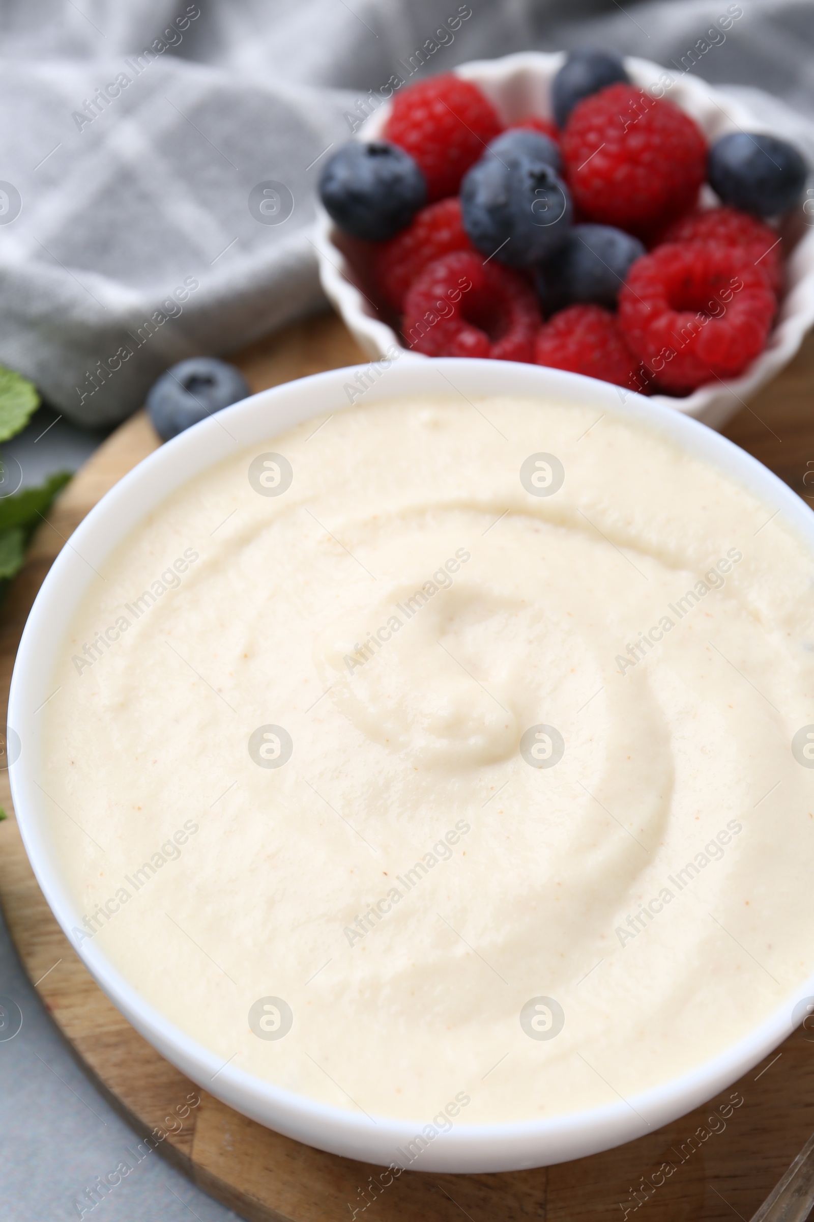 Photo of Tasty cooked semolina porridge in bowl and berries on table, closeup