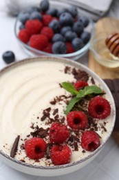 Tasty cooked semolina porridge with berries served on table, closeup