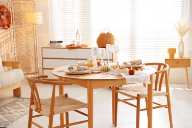 Photo of Stylish table setting with beautiful dishware and autumn decor in dining room