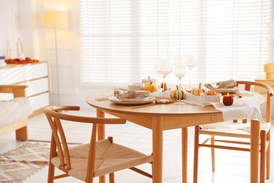 Stylish table setting with beautiful dishware and autumn decor in dining room