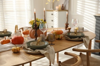 Stylish table setting with beautiful dishware, glasses and autumn decor in dining room