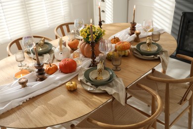 Photo of Stylish table setting with beautiful dishware, glasses and autumn decor in dining room