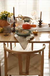 Stylish table setting with beautiful dishware, glasses and autumn decor in dining room