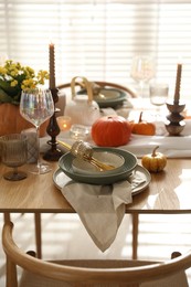 Stylish table setting with beautiful dishware, glasses and autumn decor in dining room