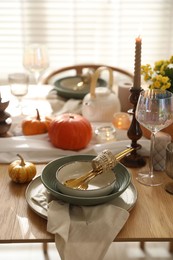 Photo of Stylish table setting with beautiful dishware, glasses and autumn decor in dining room