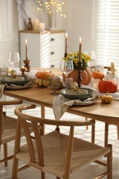 Stylish table setting with beautiful dishware, glasses and autumn decor in dining room