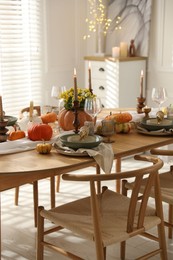 Stylish table setting with beautiful dishware, glasses and autumn decor in dining room