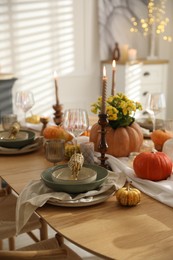 Stylish table setting with beautiful dishware, glasses and autumn decor in dining room