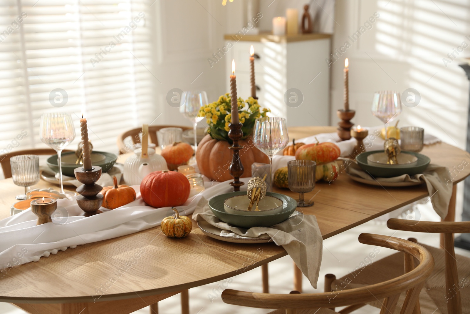 Photo of Stylish table setting with beautiful dishware, glasses and autumn decor in dining room