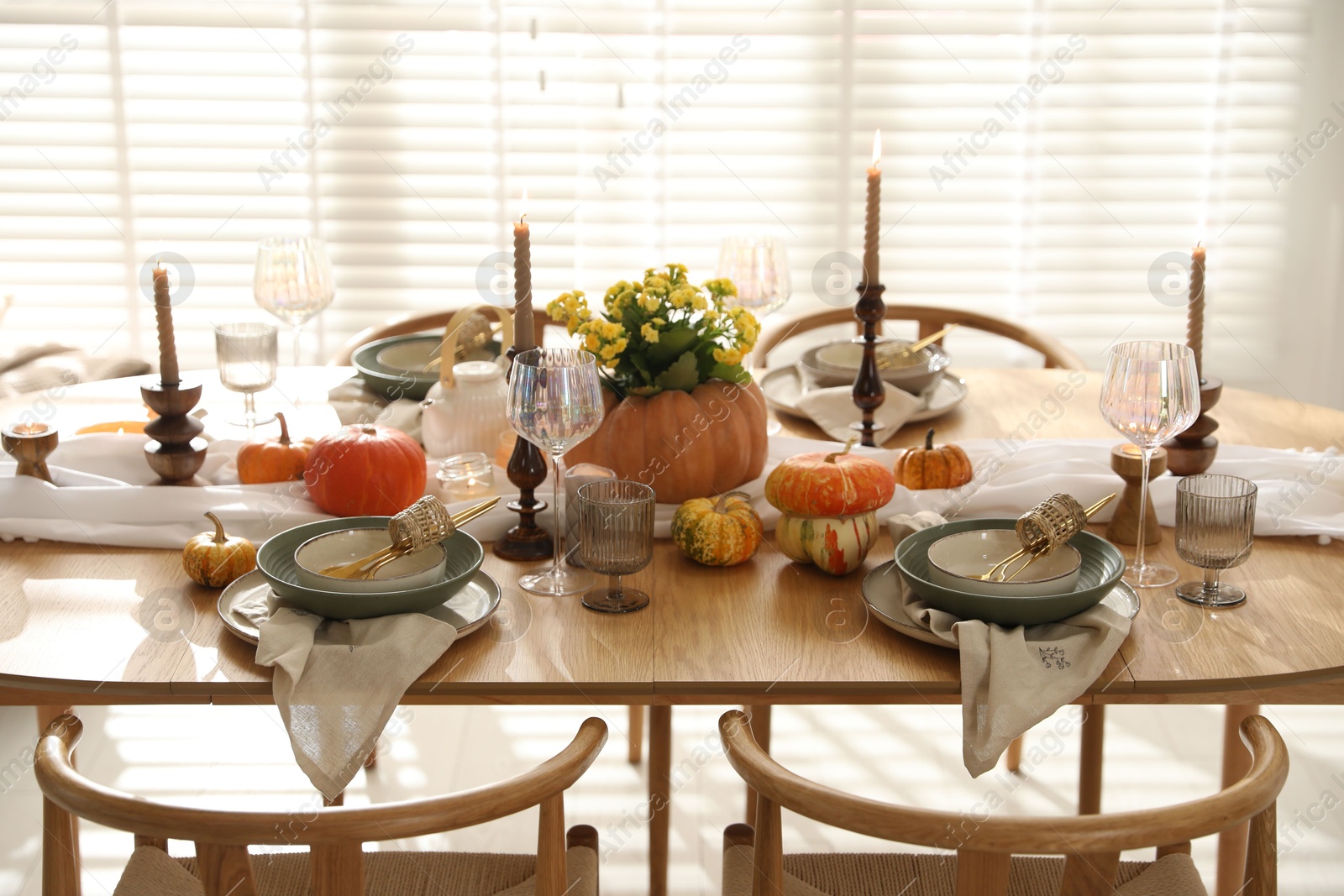 Photo of Stylish table setting with beautiful dishware, glasses and autumn decor in dining room