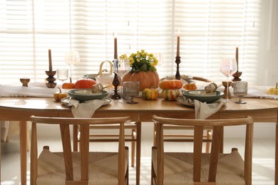 Stylish table setting with beautiful dishware, glasses and autumn decor in dining room