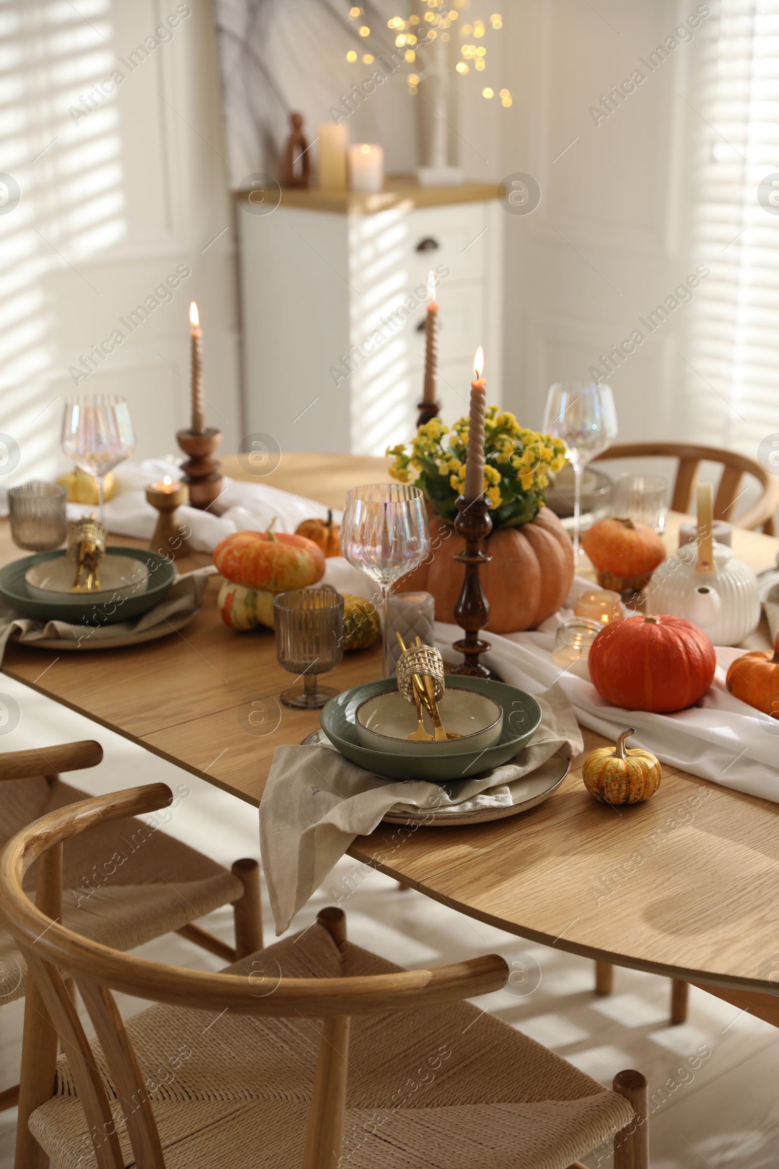 Photo of Stylish table setting with beautiful dishware, glasses and autumn decor in dining room