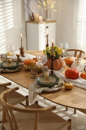 Stylish table setting with beautiful dishware, glasses and autumn decor in dining room