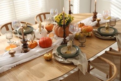 Stylish table setting with beautiful dishware, glasses and autumn decor in dining room