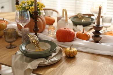 Photo of Stylish table setting with beautiful dishware, glasses and autumn decor in dining room