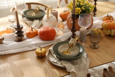 Stylish table setting with beautiful dishware, glasses and autumn decor in dining room