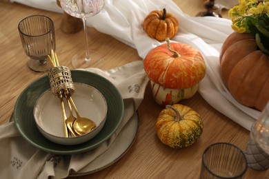 Stylish table setting with beautiful dishware, glasses and autumn decor in dining room