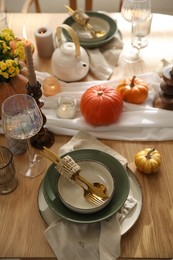 Stylish table setting with beautiful dishware, glasses and autumn decor in dining room