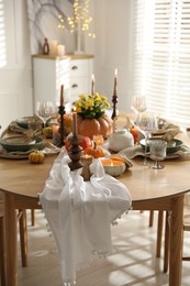 Stylish table setting with beautiful dishware, glasses and autumn decor in dining room