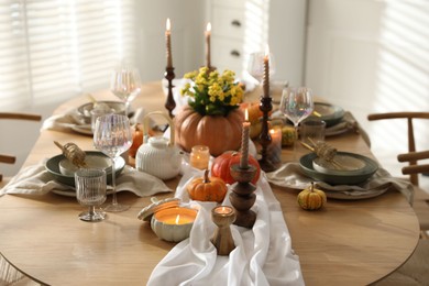 Photo of Stylish table setting with beautiful dishware, glasses and autumn decor in dining room