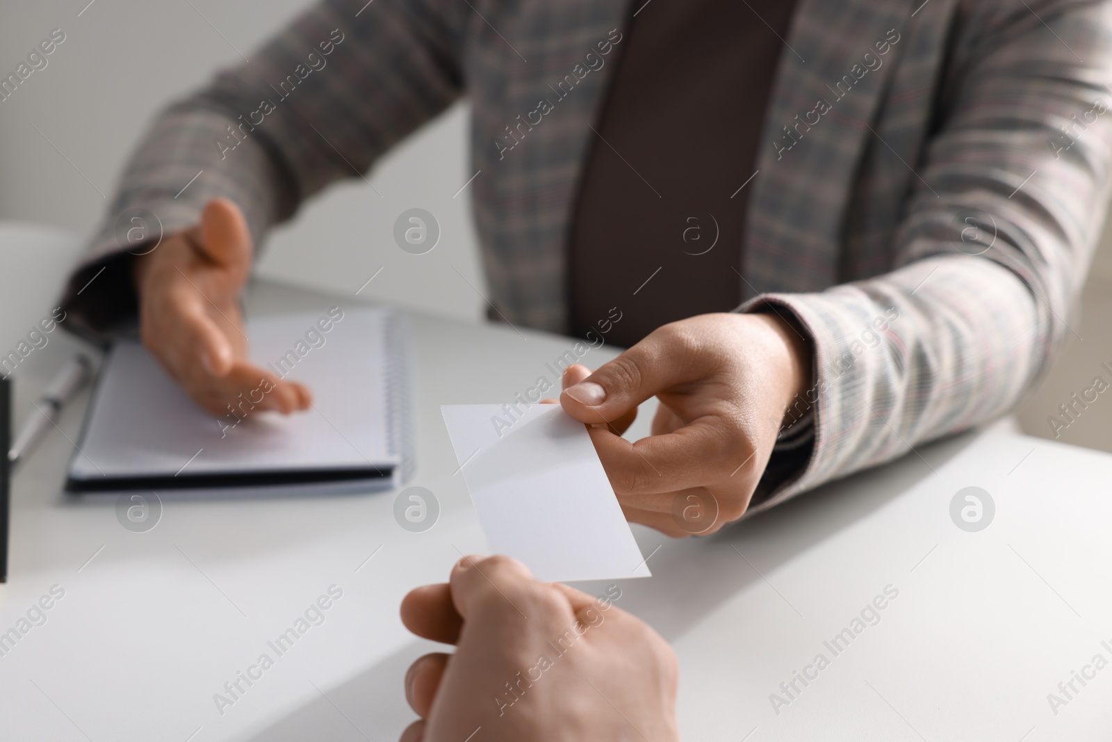 Photo of Woman giving business card to man at table in office, closeup. Mockup for design