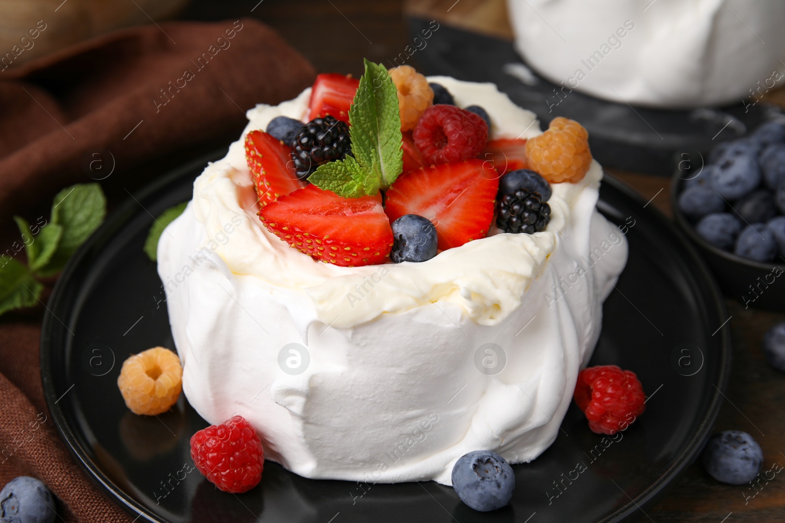 Photo of Pavlova cake (meringue dessert) with whipped cream, fresh berries and mint on table, closeup