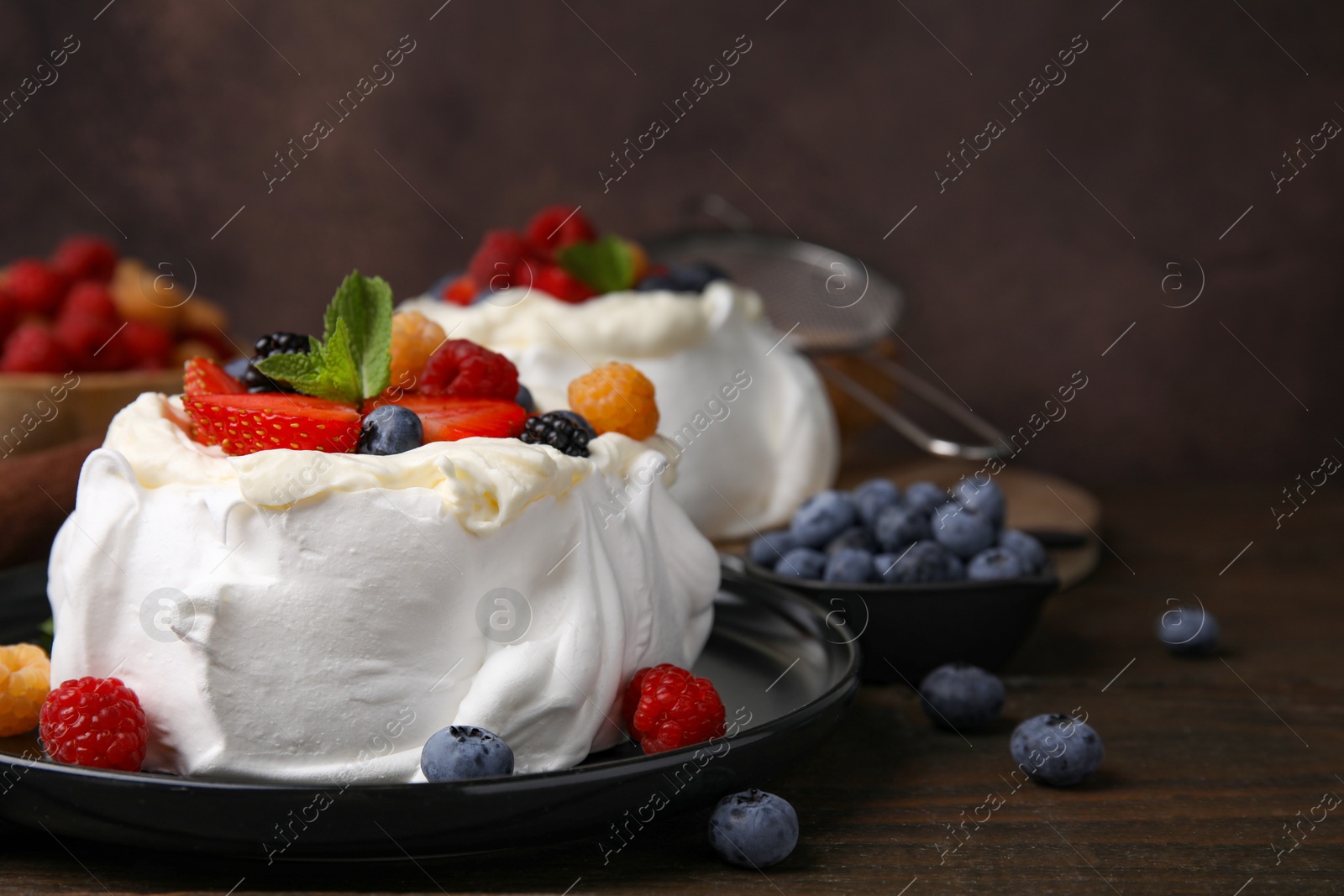 Photo of Pavlova cake (meringue dessert) with whipped cream, fresh berries and mint on wooden table, closeup