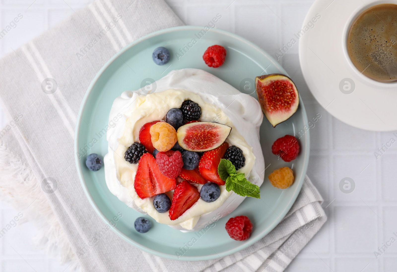 Photo of Pavlova cake (meringue dessert) with whipped cream, fresh berries, mint and fig on white tiled table, top view