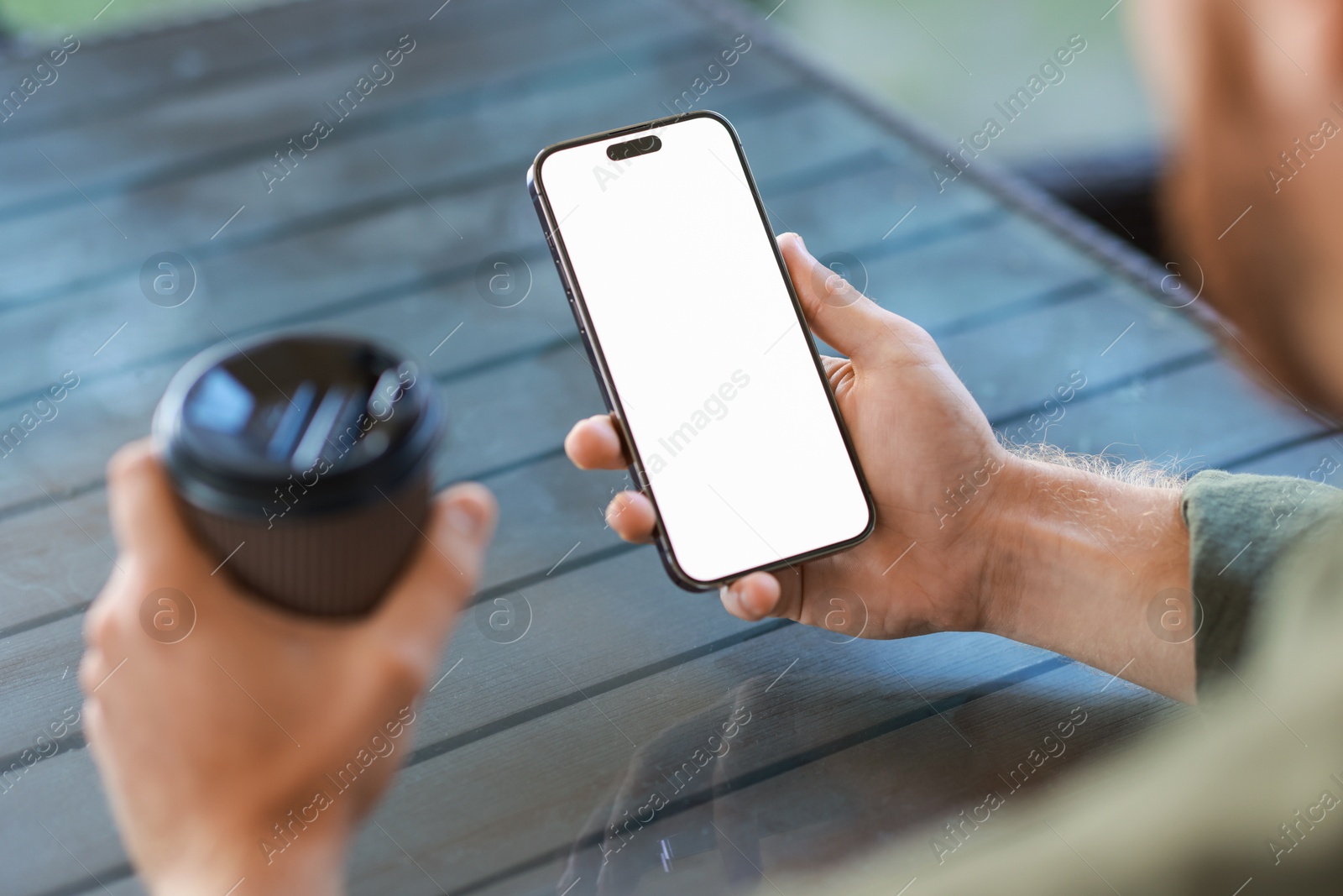 Photo of Man with paper cup using smartphone at outdoor cafe, closeup. Space for design