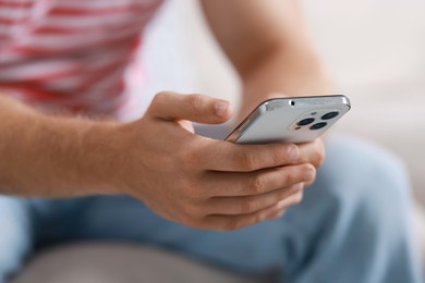 Man using smartphone on blurred background, closeup