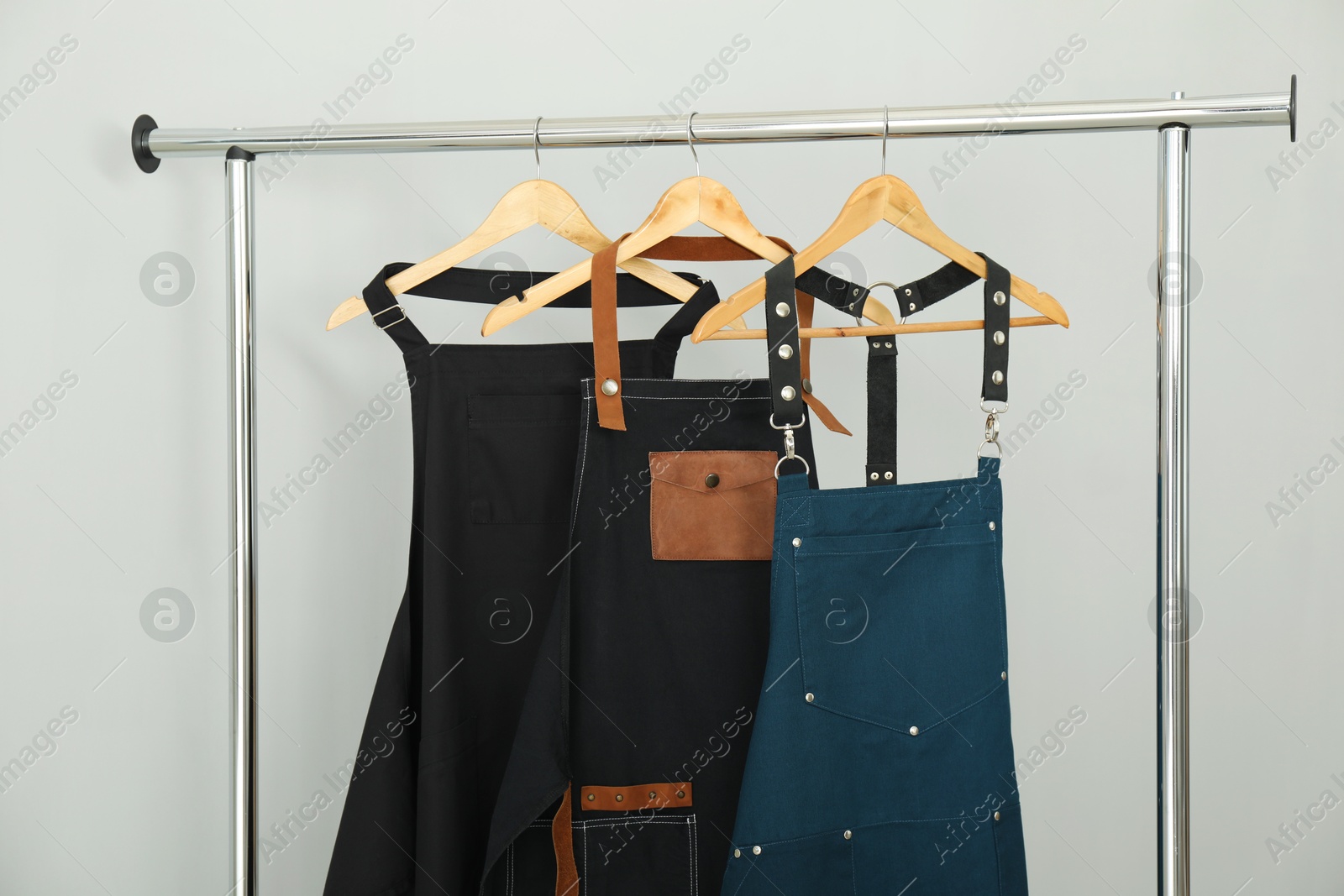 Photo of Aprons on clothing rack near light grey wall