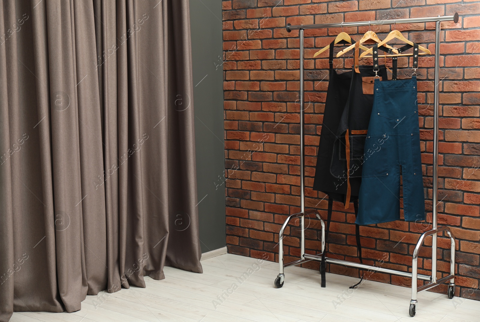 Photo of Many chef's aprons hanging on brick wall