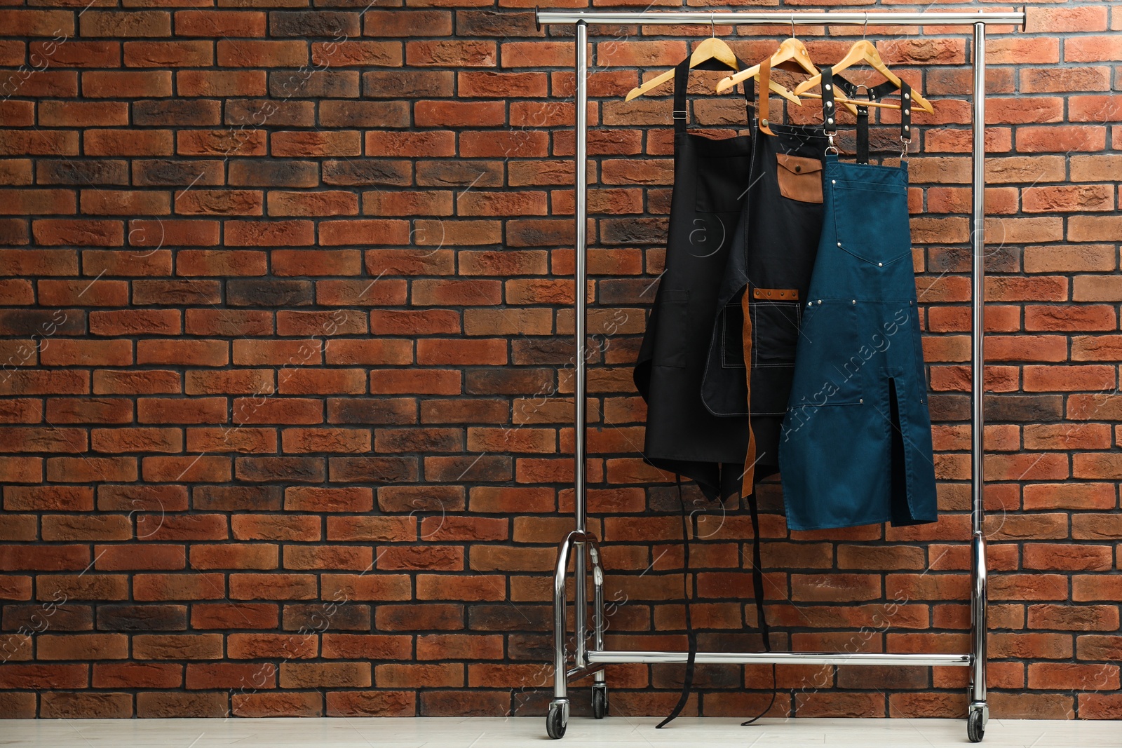 Photo of Many chef's aprons hanging on brick wall