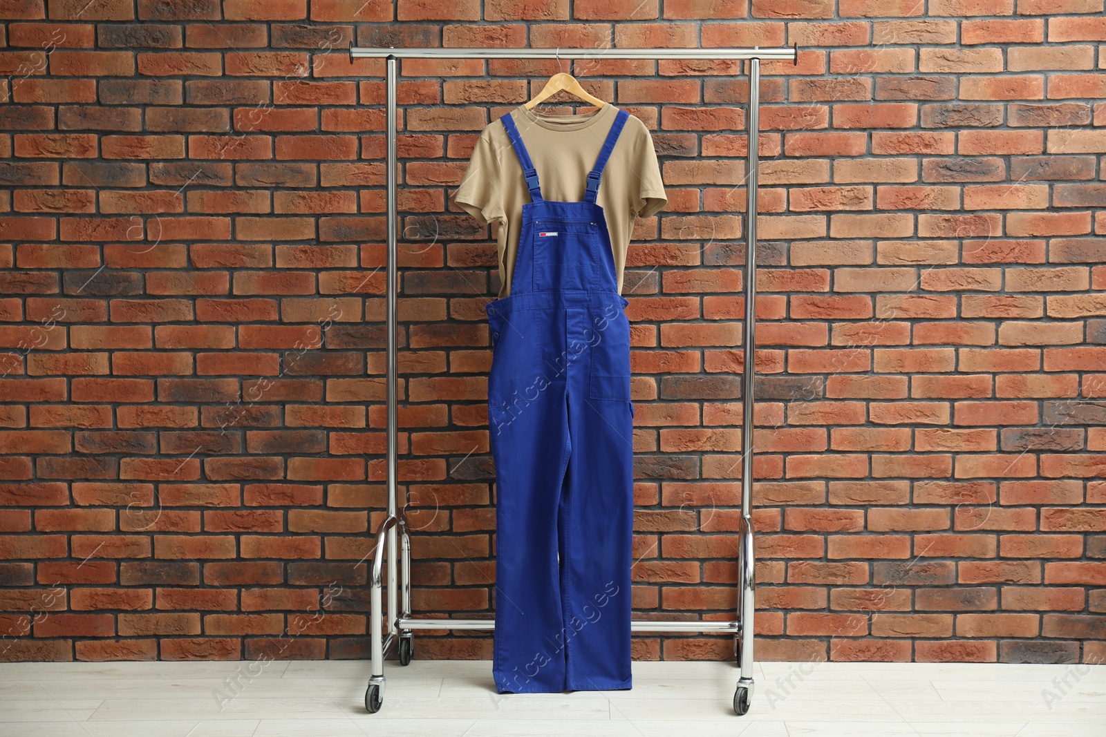 Photo of Workers' uniform on clothing rack near brick wall