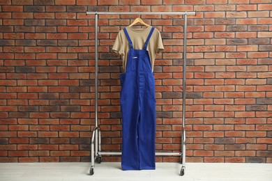 Photo of Workers' uniform on clothing rack near brick wall