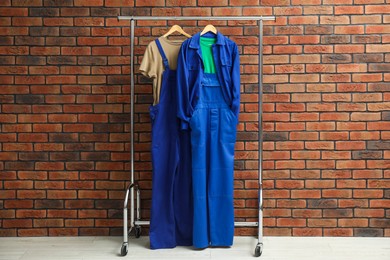 Photo of Workers' uniforms on clothing rack near brick wall